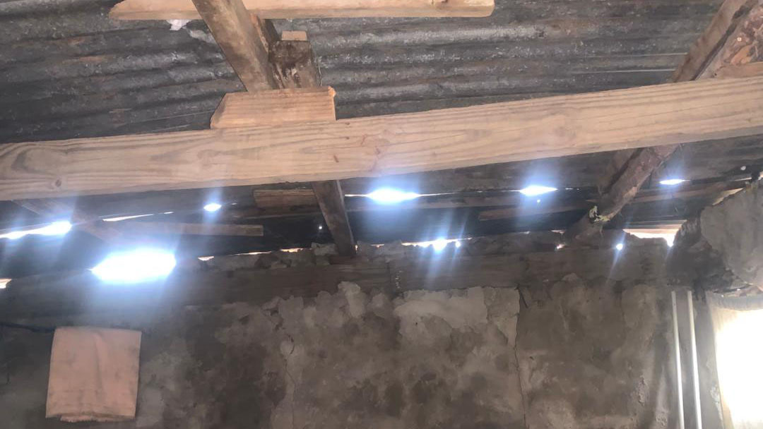 The storm left the roof severely damaged, with visible gaps exposing the interior of the homestead. 